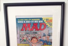 Gerahmtes, unveröffentlichtes Titelbild der US-Ausgabe MAD #411 von John Caldwell. Alfred E. Neuman rennt beim New York Marathon lachend durch ein Polizei-Absperrband an einem Tatort.