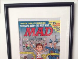 Gerahmtes, unveröffentlichtes Titelbild der US-Ausgabe MAD #411 von John Caldwell. Alfred E. Neuman rennt beim New York Marathon lachend durch ein Polizei-Absperrband an einem Tatort.