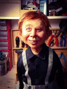 Fast fertige, realistische Alfred E. Neuman Büste mit roten Haaren, Zahnlücke, schwarzem Hemd und Hahnentritt-Hosenträgern auf der Werkbank.